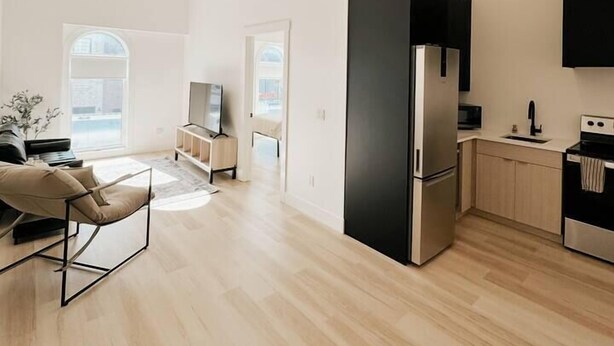 A modern kitchen with a large black refrigerator, a stove, and a microwave. - The Charlotte • King Bed • Downtown Woodstock (Woodstock)