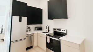 A modern kitchen with a built-in oven, microwave, and coffee maker. - The Charlotte • King Bed • Downtown Woodstock (Woodstock)