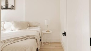 A minimalist bedroom with a bed, bedside table, and a framed picture on the wall. - The Charlotte • King Bed • Downtown Woodstock (Woodstock)