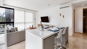 Una cocina moderna con una isla central, un televisor de pantalla plana montado en la pared y un ventanal con vistas al exterior.