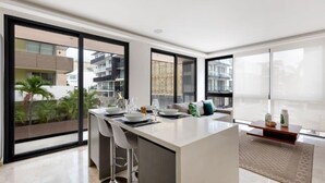 Una cocina moderna con una isla central, taburetes de bar y un comedor.