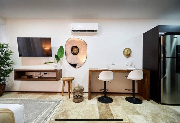 A modern kitchen with a built-in refrigerator, a flat-screen TV, and a wooden dining table with two chairs.