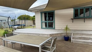 Un espace patio avec une table et des bancs en bois, un trampoline et une plante en pot.