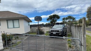 Une allée privée, fermée par un portail, mène à une propriété résidentielle où un véhicule est garé.