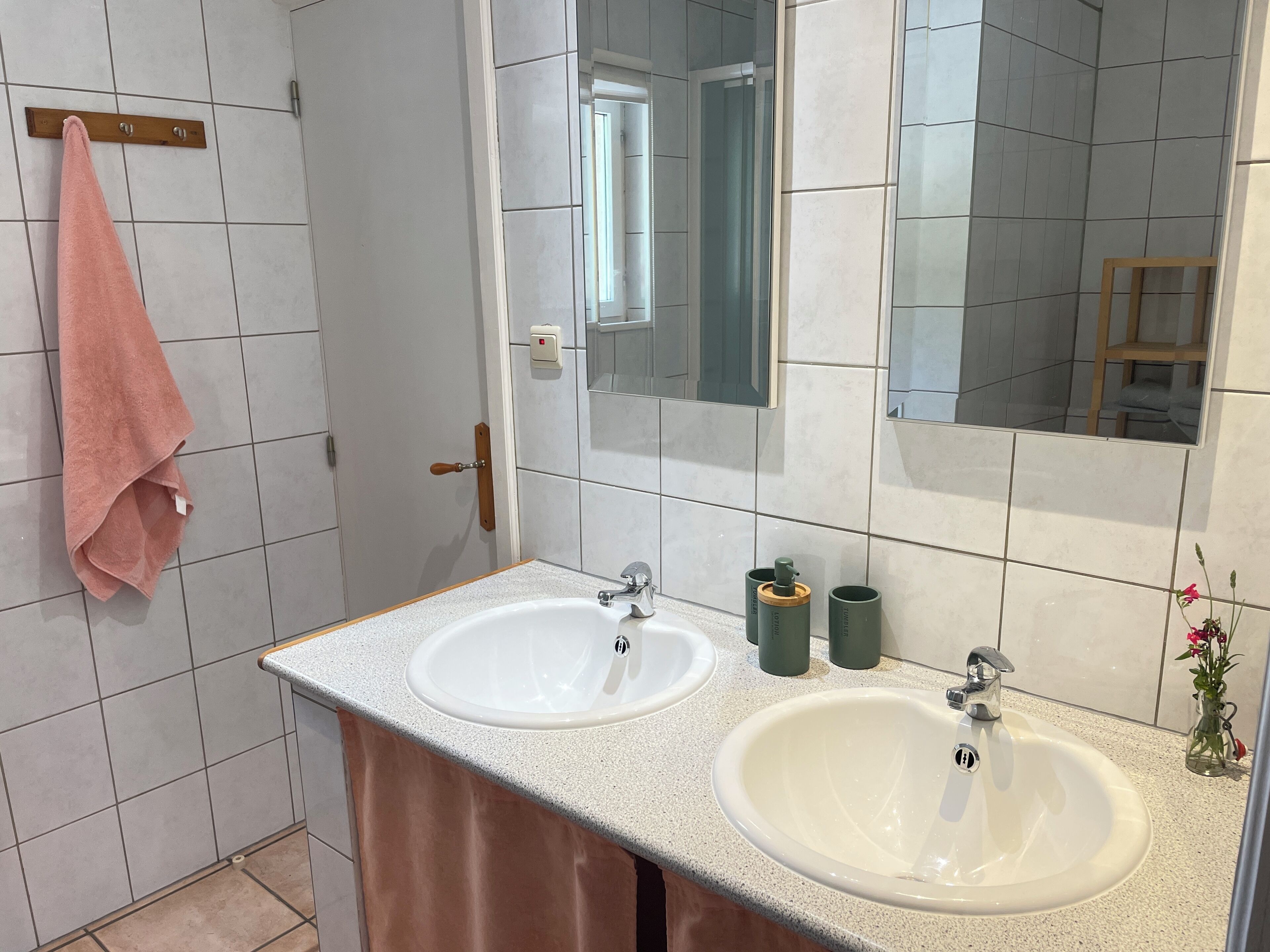 A bathroom with two sinks, a mirror, and a towel rack.