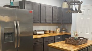 A modern kitchen with dark cabinets, stainless steel appliances, and a wooden countertop.