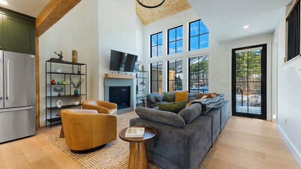 A spacious living room with a fireplace, a large sofa, and a television. - Luxury Mountain Escape (North Conway)