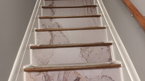 Un escalier dont les marches sont recouvertes d’un matériau qui ressemble au marbre, et une inscription au-dessus qui dit : « restez un peu ».