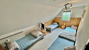 Un dormitorio con tres camas literas, una pared de madera, un ventilador de techo y una ventana con vistas.