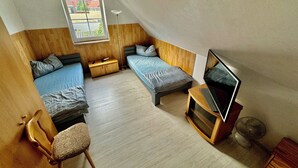 Una habitación pequeña con dos camas, un escritorio y un televisor.