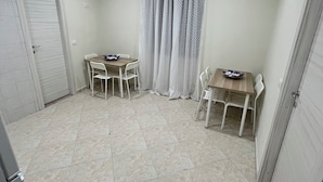 Une pièce avec deux tables et des chaises, une porte et un rideau.