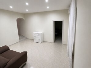 A room with a brown sofa, a white cabinet, and a door leading to another room.