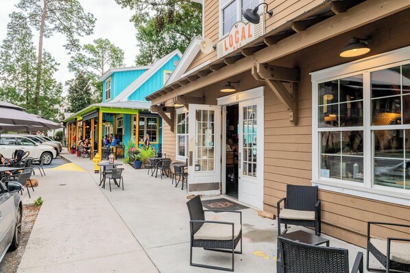 An outdoor seating area with tables and chairs, a building with a 'LOCAL PIE' sign, and a blue storefront in the background. - Spacious 4 Bedroom, 4 Bath Townhome in Historic Old Town Bluffton (Bluffton)