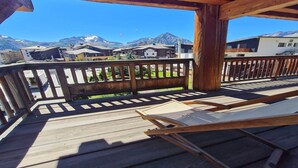 Une terrasse en bois offrant une vue sur une chaîne de montagnes et des bâtiments.
