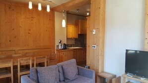 En inredning med träpanel, en soffa, ett matbord och en tv.