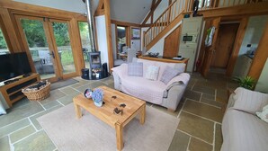 Un salon chaleureux avec un sol en pierre, une table basse en bois, un canapé et un téléviseur.