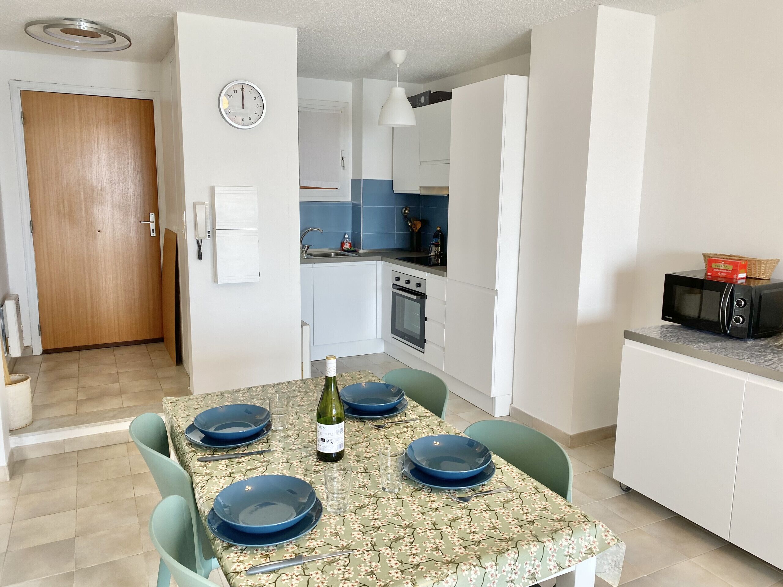 Una cucina compatta con mobili bianchi, un forno a microonde e un lavello.