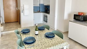 Una cocina compacta con armarios blancos, un microondas y un lavamanos.