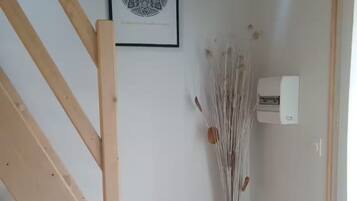 A wooden staircase with a simple design, a framed artwork on the wall, and a decorative plant in a black pot.