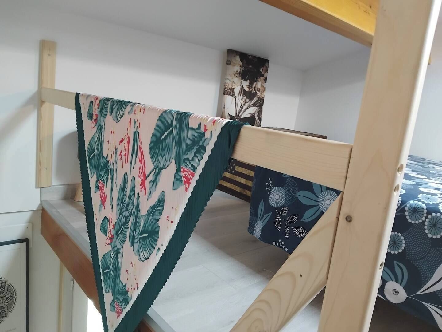 Een stapelbed met een bloemenprintdeken over het onderste bed.
