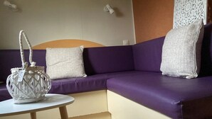 A purple sofa with two pillows and a white woven basket on a small round table.