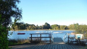 A wooden dock leading to a calm lake with boats.