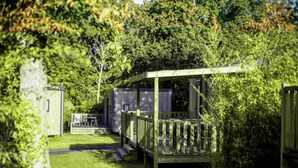 A wooden deck with a railing, a small table, and a bench. - ZEcamping 5* animé parc aquatique fitness locatif TV LV BBQ 28m2 (Quimper)