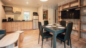 A modern kitchen with a dining area, wooden cabinets, a refrigerator, and a flat-screen TV. - ZEcamping 5* animé parc aquatique fitness locatif TV LV BBQ 28m2 (Quimper)