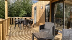 A wooden deck with outdoor furniture, a glass door, and a wooden wall. - ZEcamping 5* parc aquatique club enfant fitness locatif BBQ 2 pers (Quimper)