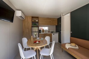 Une cuisine compacte avec un coin repas, un canapé et un téléviseur fixé au mur.