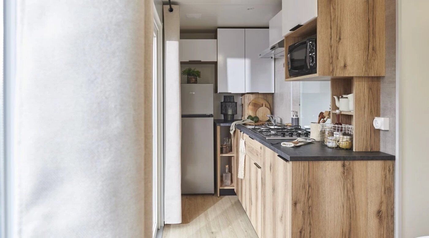 A modern kitchen with wooden cabinets, a black countertop, and a microwave.