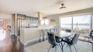 A modern kitchen with a central island, bar stools, and a dining area with a large table and chairs. - Charming 2-bedroom unit with WiFi, AC with amazing Puget Sound view in Tacoma (Tacoma)