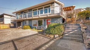A two-story house with a balcony, a red door, and a stone staircase leading to the entrance. - Charming 2-bedroom unit with WiFi, AC with amazing Puget Sound view in Tacoma (Tacoma)