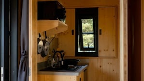 Cocina pequeña con paredes de madera, una ventana y electrodomésticos básicos.