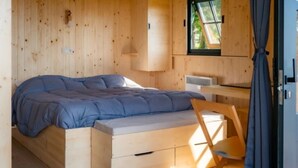 Una habitación de cabaña de madera con una cama, un escritorio y una ventana.