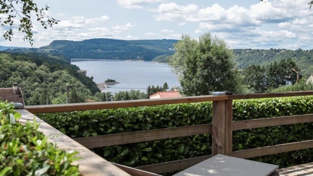Una terraza de madera con vista a un lago y colinas.