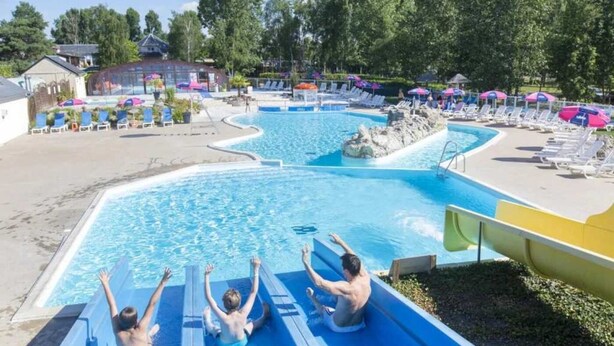 Ein Schwimmbecken mit Wasserrutsche, Liegestühlen und Sonnenschirmen.