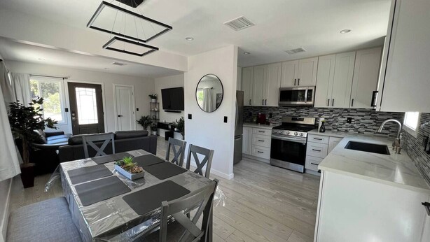 A modern kitchen with white cabinets, a stainless steel microwave, and a built-in oven. - Cheerful house with EV, Parking & backyard (Culver City)