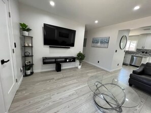 A modern living room with a flat-screen TV, a glass coffee table, and a grey sofa. - Oasis 2BR Culver City: 6 Miles to SoFi Stadium (Culver City)