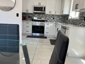 A modern kitchen with white cabinets, a stainless steel oven, and a black and white tiled backsplash. - Oasis 2BR Culver City: 6 Miles to SoFi Stadium (Culver City)