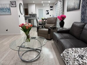 A modern living room with a glass coffee table, a leather sofa, and a dining area in the background. - Oasis 2BR Culver City: 6 Miles to SoFi Stadium (Culver City)