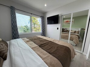 A hotel room with a large bed, a TV mounted on the wall, and a sliding door leading to a balcony. - Oasis 2BR Culver City: 6 Miles to SoFi Stadium (Culver City)