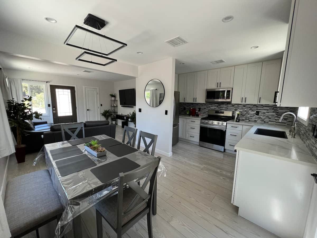 A modern kitchen with white cabinets, a built-in microwave, and a stainless steel refrigerator.