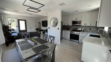 A modern kitchen with white cabinets, a built-in microwave, and a stainless steel refrigerator.