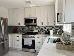 A modern kitchen with white cabinetry, a stainless steel refrigerator, a microwave, a stove, and a sink. - Oasis 2BR Culver City: 6 Miles to SoFi Stadium (Culver City)