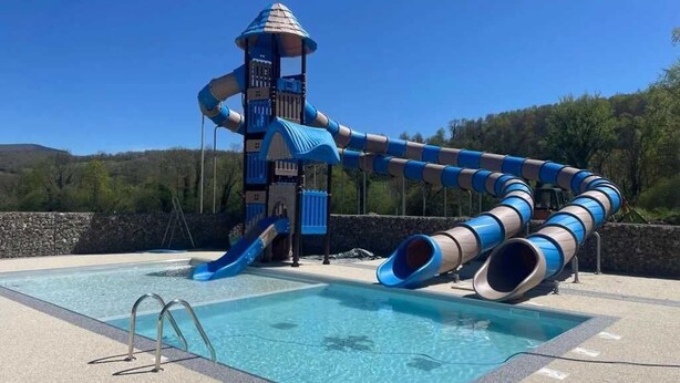 Una piscina con un tobogán y una estructura de juegos.