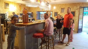 Eine Bar mit Hockern, einer Theke und einer stehenden Person.
