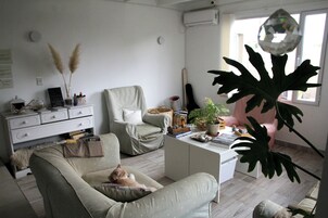 Una sala de estar con un sofá, una silla, una mesa de centro y una planta grande.