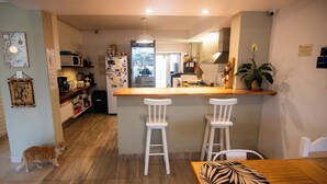 Una cocina con mostrador de madera, dos taburetes blancos, un gato y un perro.