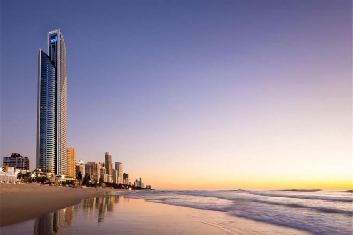 A beachfront hotel with a tall building, a sandy beach, and the ocean.